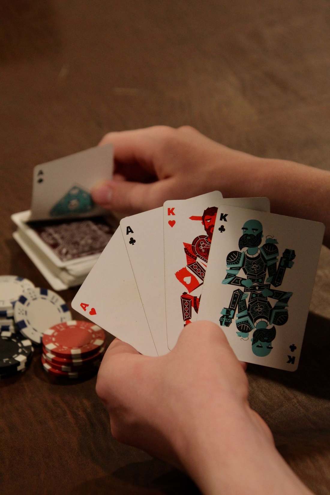 Tangan memegang kartu as dan keripik poker di atas meja