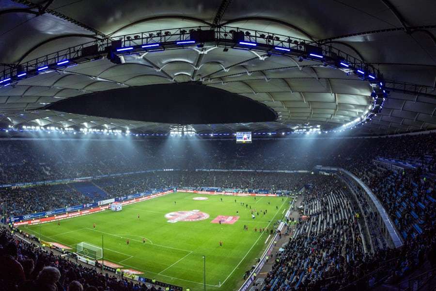 Lapangan sepak bola dengan stadion menyala di malam pertandingan